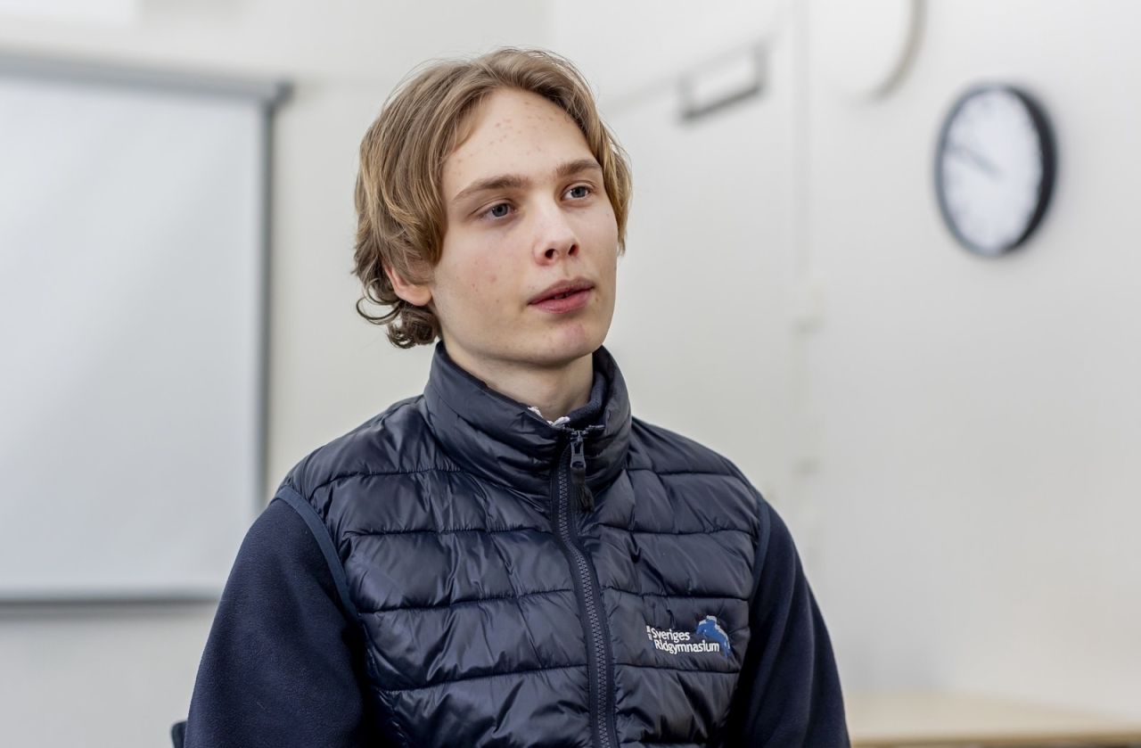 Ung man i quiltad väst i en skolmiljö