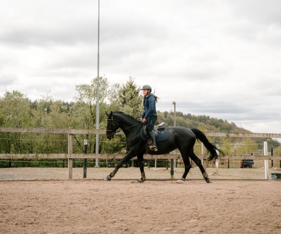 Elev rider på en svart häst på ridbanan i Kungsbacka